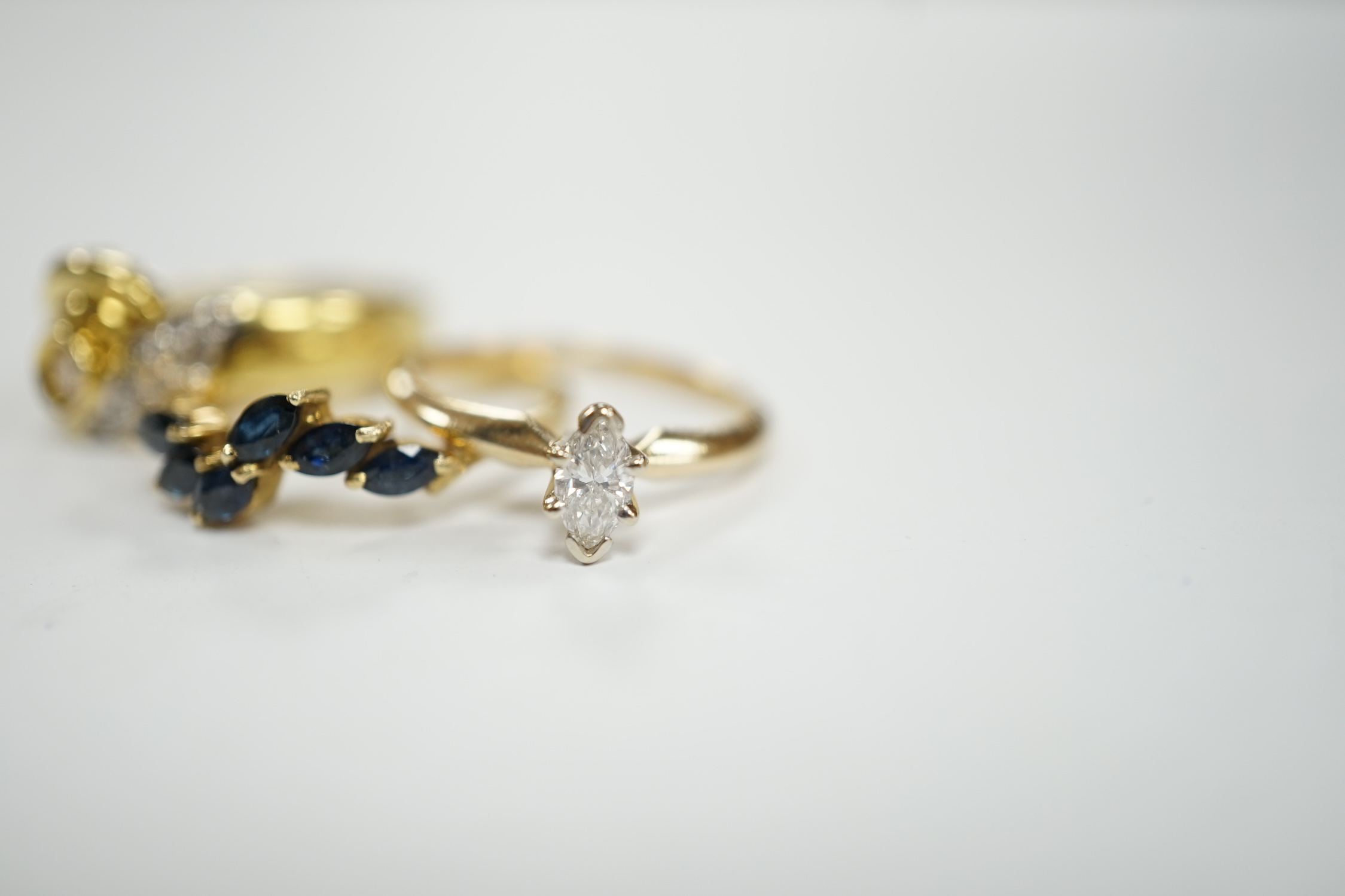 Three assorted modern 14k and gem set rings, including single stone marquise cut diamond, diamond chip set and sapphire set, gross weight 7.7 grams.